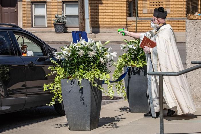 A Roman Catholic priest in the Detroit area using a squirt gun to shoot holy water.