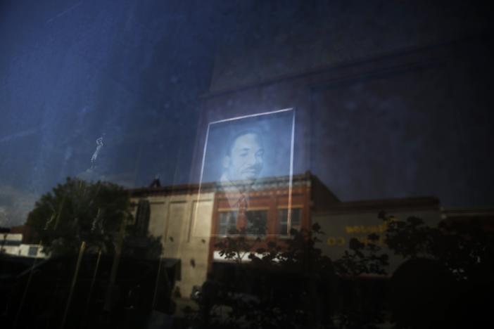 Downtown Dawson, Ga., is reflected in the window of a local barber shop where a photograph of Martin Luther King Jr. is on display on Friday, April 17, 2020. 