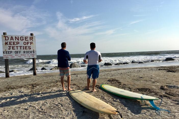 Surfers contemplating waves at Tybee Island.