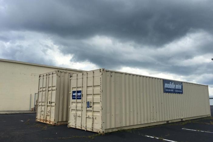 Two rented shipping containers behind the Macon-Bibb County Board of Elections represent just one of the added expenses for the state's new voting machines.