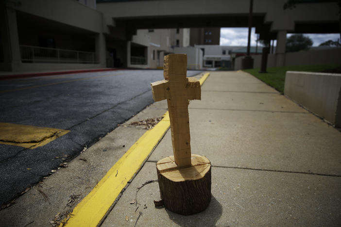 A wooden cross made from a tree stump, known by some locals as a symbol of hope, sits outside of Phoebe Putney Memorial hospital on Monday, April 20, 2020, in Albany, Georgia. 
