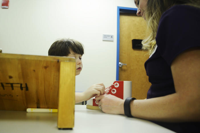 Alex Rayburn, seven,  practices tying and untying a shoe with the help of physical therapist Kathryn Staples at the Autism Center at Navicent Health in Macon. 