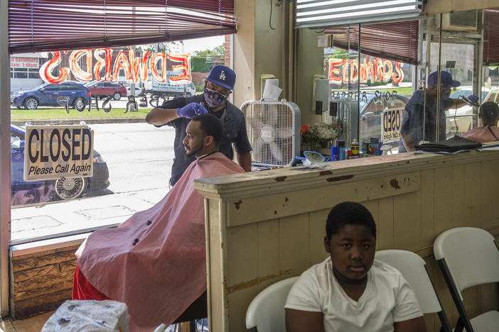 Barber Marian Searcy cuts Shaquille Sanders' hair in the shop Searcy helps run in downtown Macon Friday. "Just me being a man and the stress of me being a man, to provide for my household, that's my drive for coming back to work," Searcy said.