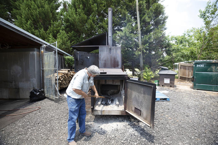 Phillip Crowe stokes the fire box of a barbecue smoker outside Crowe's Bar-B-Que in Madison.