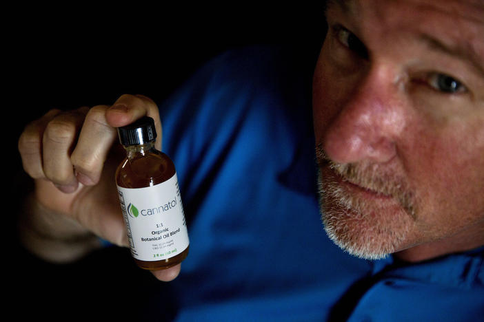 In this Monday, April 17, 2017 photo, Georgia State Rep. Allen Peake, R - Macon, displays a bottle of cannabis oil in his office in Macon, Ga. Peake is at the center of a semi-legal statewide medical cannabis distribution network.