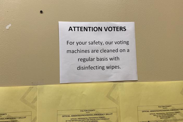 A sign about cleaning voting machines greets voters at the Fulton County Government Center polling place.