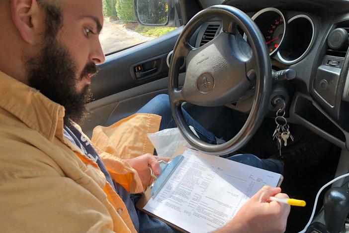 Whit Whitmire of Compostwheels checks a list of homes he has to visit to pick up food waste that will eventually be turned into compost.