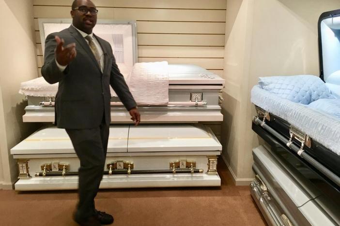 Funeral home owner Richard Robinson leads reporters through his casket showroom as an example of how he plans tours for young people in an effort to curb deadly violence in Macon.