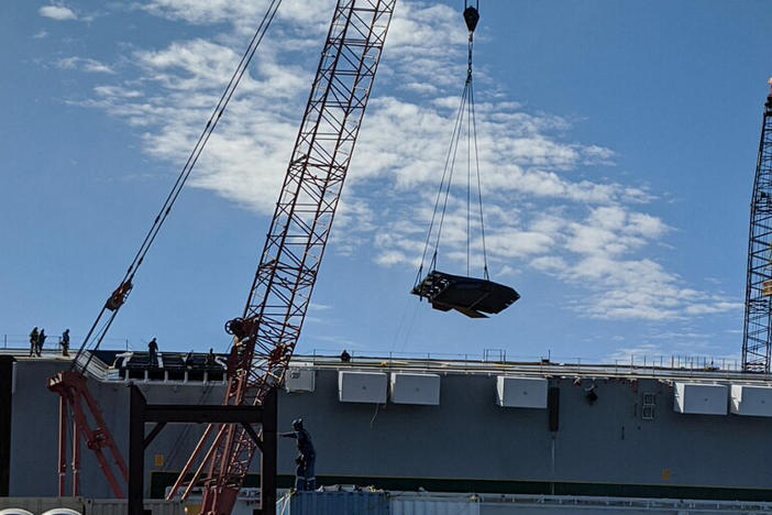 Contractors remove a ramp from the Golden Ray, which is capsized in St. Simon's Sound. The plan to cut up and remove the vessel has been announced.
