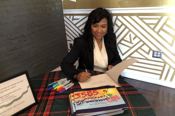 Author of "3,585 Miles to be an American girl", Nury Castillo-Crawford signs a page of her book at a book release.