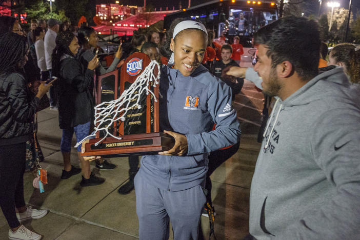 Mercer's KeKe Calloway carries the SoCon Basketball Tournament trophy off the team bus as she and the rest of the Bears arrive back on Mercer's campus Sunday night. Winning the conference title means the Bears advance to the NCAA Tournament.