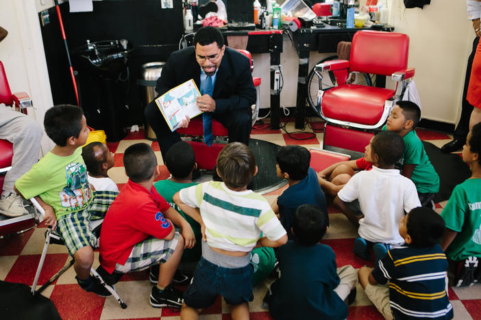 U.S. Education Secretary John King reads to a group of school-aged children. He recently advised governors and state school leaders to do away with corporal punishment.