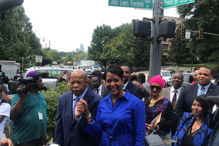 Mayor Keisha Lance Bottoms and Congressman John Lewis join hands undeneath his new street sign.