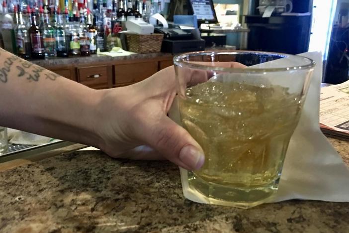 Bartender Valeri Herring puts down a drink at the bar of 20s Pub on Riverside Drive. Herring recently applied to renew the bar's alcohol license but many others in Macon-Bibb County have yet to apply