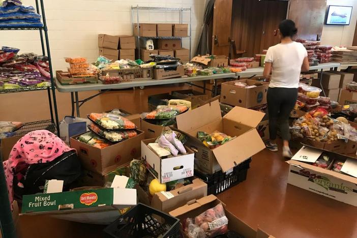 A volunteer at Malachi's Storehouse arranges produce for the 150 people who visit each Wednesday to get groceries.