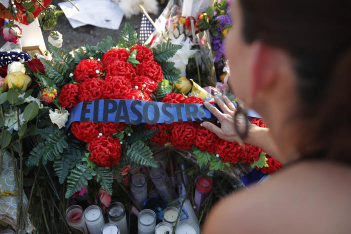 A woman leaves flowers at a makeshift memorial at the scene of a mass shooting at a shopping complex Tuesday, Aug. 6, 2019, in El Paso, Texas. 