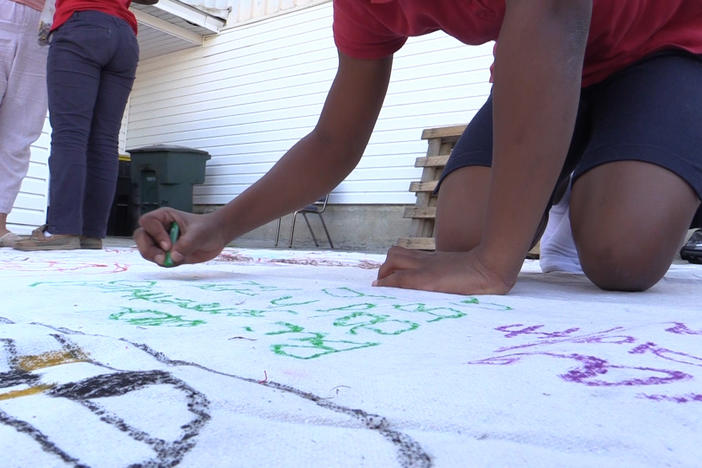 Student draws on peace mural, to go up in her neighborhood. 