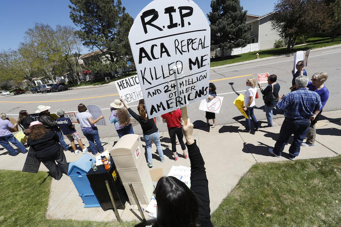Lisa Moore of Denver holds up a sign during a protest outside the office of U.S. Rep. Mike Coffman, R-Colo., over the health care overhaul bill up for a vote in the U.S. House Thursday, May 4, 2017, in Aurora, Colo.