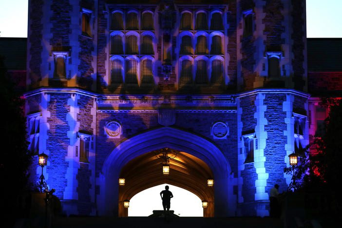 A man jogs up stairs to Brookings Hall, which is lit up in a patriotic theme, as preparations continue ahead of the second presidential debate at Washington University in St. Louis this Sunday.