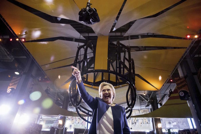 A large depiction of a football helmet hangs from the ceiling as Democratic presidential candidate Hillary Clinton points to members of the crowd after speaking at a rally at Heinz Field in Pittsburgh, Friday, Nov. 4, 2016.