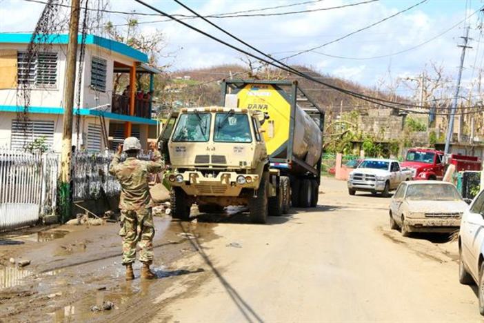 A Puerto Rico Army National Guardsman guides a truck transporting water. 