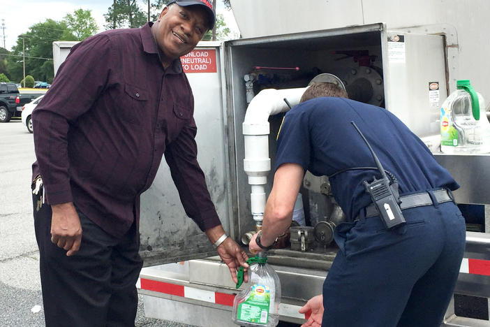 Milledgeville resident James Rayford receives assistance filling plastic containers with sanitized water from Milledgeville Fire Fighter Patrick McCulley. Rayford said he was out getting water for someone who is unable to leave their home.