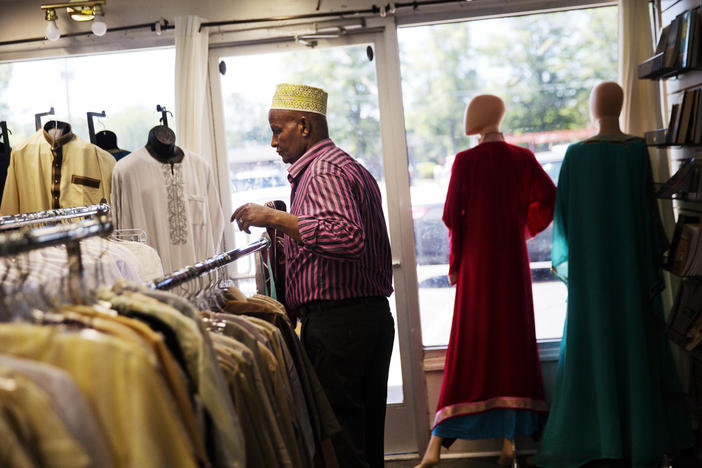Mohamoud Saed, a refugee from Somalia, helps out in a friend's clothing store in Clarkston, Ga., Tuesday, May 2, 2017. 
