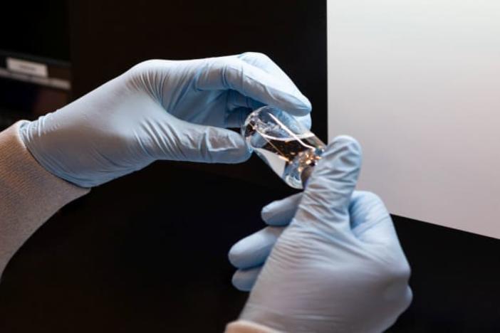 A lab technician visually inspects a filled vial of investigational coronavirus disease (COVID-19) treatment drug remdesivir at a Gilead Sciences facility in La Verne, California, March 11, 2020.