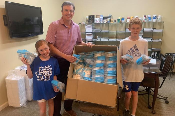 Ryan Casey with his children, Sydney and Gray, as they unload KN95 repirator masks.