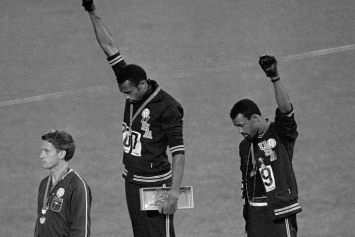 Gold medallist Tommie Smith (center) and bronze medalist John Carlos (right) raise their fists on the podium after the 200 m race at the 1968 Summer Olympics;