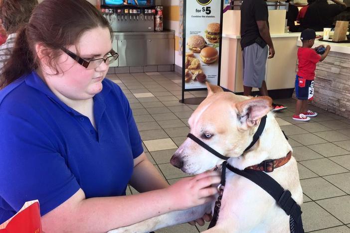 Bonny O'Donnell comforts for service dog, Carson, at a McDonald's in Savannah, GA. O'Donnell relies on Carson to help her handle post-traumatic stress caused by school bullying.