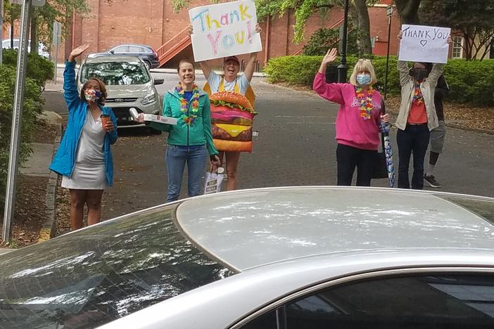 A group gathered outside Emmaus House with donuts and "thank you" signs on the soup kitchen's last day serving meals for the time being.