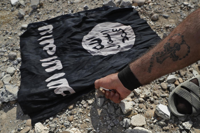 A fighter of Christian Syriac militia that battles the Islamic State group under the banner of the U.S.-backed Syrian Democratic Forces, burns an IS flag on the front line on the western side of Raqqa, northeast Syria, Monday, July 17, 2017. 