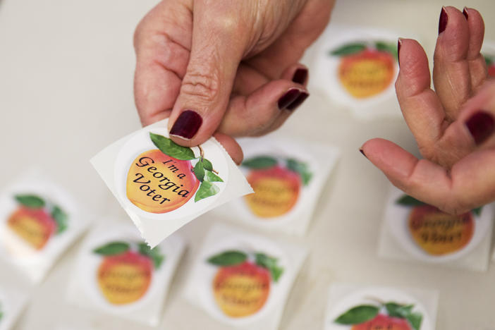 A Poll worker hands a sticker to a voter after they casted their ballot in Georgia's primary election at a polling site Tuesday, March 1, 2016, in Atlanta.