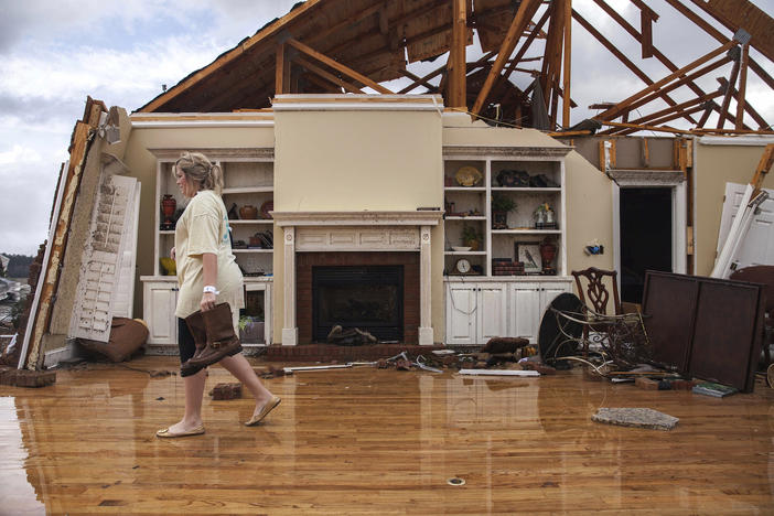 Jenny Bullard carries a pair of boots from her home that was damaged by a tornado, Sunday, Jan. 22, 2017, in Adel, Ga. 