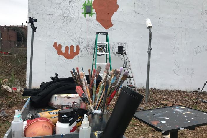 Yungai's paintbrushes sit in front of the wall where he paints his mural.