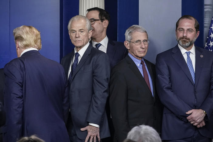 White House economic adviser Peter Navarro (center, left) and Dr. Anthony Fauci, director of the National Institute of Allergy and Infectious Diseases, stand back to back after a White House Coronavirus Task Force briefing on March 9. Navarro wrote an opinion article this week criticizing Fauci.