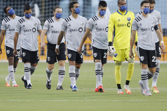 Members of the Montreal Impact, wearing masks, take the field for their match against Toronto FC as part of the MLS Is Back Tournament Thursday in Reunion, Fla.