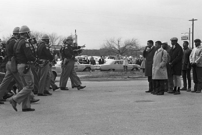 Protesters, including John Lewis (tan trenchcoat), and police officers stand off on Bloody Sunday, March 7, 1965, in Selma, Alabama.