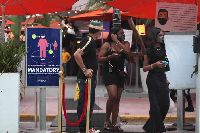 People leave the Ocean 10 restaurant as a curfew from 8 p.m. to 6 a.m. is put in place on Saturday in Miami Beach, Fla.