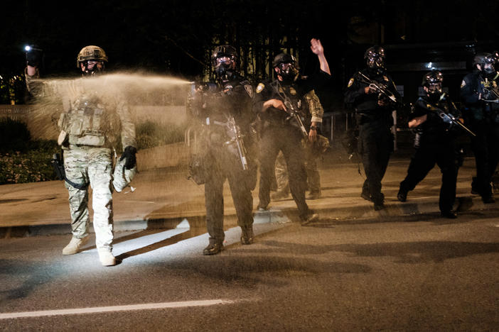 Federal officers use tear gas and other crowd dispersal munitions on protesters Friday outside the Multnomah County Justice Center in Portland, Ore.