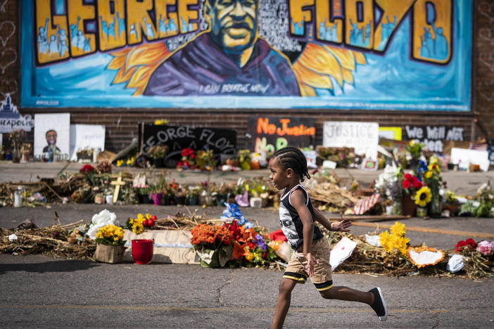 The Minnesota Legislature has approved a bill to revise rules on police use of force in response to the killing of George Floyd. Here, a boy runs past a mural at a memorial to Floyd outside Cup Foods.