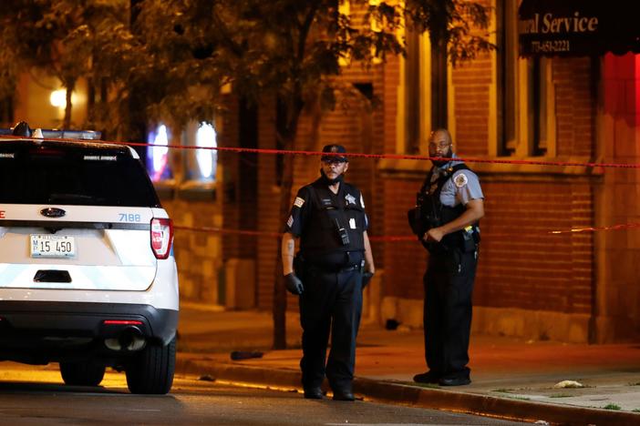 Chicago Police Department officers stand in front of Rhodes Funeral Services as they investigate the scene of a shooting Tuesday night. Gun violence outside a funeral left at least 15 people wounded.