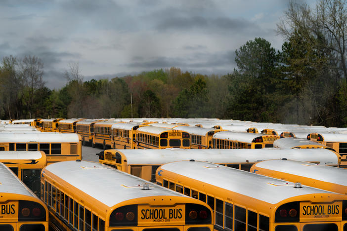 School buses sit parked at a lot in Marietta, Ga., in March. Georgia Gov. Brian Kemp has pushed for students to return to school in the fall, but the state's largest system, in Gwinnett County, has decided on all-virtual learning.