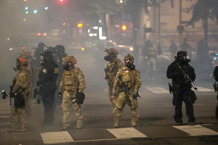 Federal police stand guard on Salmon Street after pushing protesters away from the Mark O. Hatfield U.S. Courthouse on Tuesday in Portland, Ore. The federal police response to the ongoing protests against racial inequality has been criticized by city and state elected officials.
