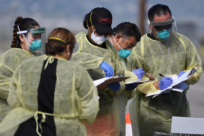 Medical personnel from Riverside University Health Systems hospitals administer a coronavirus test to an individual during drive-through testing in the parking lot of Diamond Stadium on March 22 in Lake Elsinore, Calif.