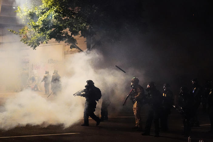 Federal officers walk through tear gas while dispersing a crowd during a July 21 protest in Portland, Ore. A temporary restraining order on Thursday blocked federal agents from knowingly targeting journalists and legal observers.