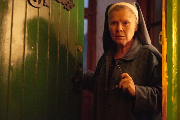 A mischievous nun (Imelda Staunton) welcomes a stranger into a decrepit house in the supernatural thriller <em>Amulet</em>.
