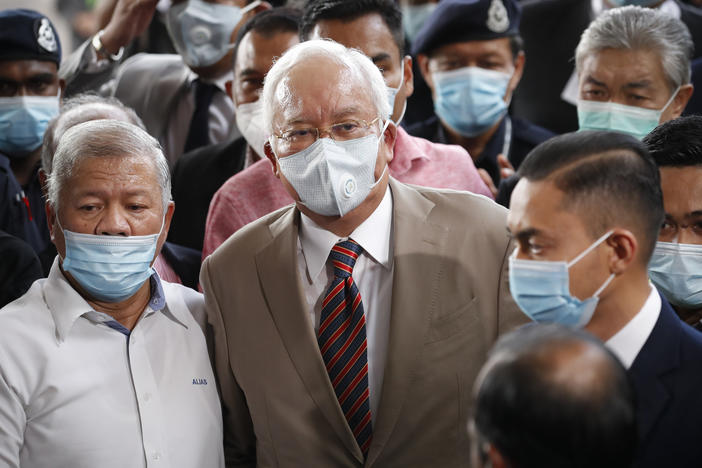 Former Malaysian Prime Minister Najib Razak (center), wearing a face mask with his supporters, arrives at the courthouse in Kuala Lumpur, Malaysia, on Tuesday. Najib was found guilty of corruption in the first of several trials linked to the multibillion-dollar looting of the 1MDB state investment fund.