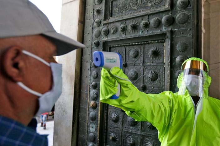 A medic checks the temperature of a Syrian worshipper before entering the Umayyad Mosque in Damascus to attend Friday prayer on May 15. To try to slow the coronavirus outbreak, the Syrian government has banned mass prayers and asked Syrians to stay home over the Muslim holiday of Eid al-Adha this weekend.